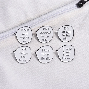 Set of 6 white speech bubble enamel pins with motivational quotes on a canvas bag