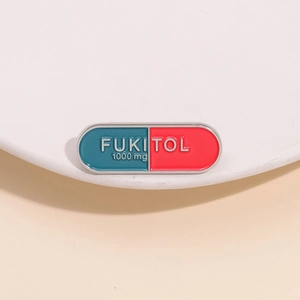 Capsule shaped enamel brooch in blue and red featuring creative FUKITOL text engraving