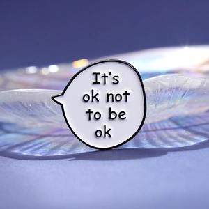 White speech bubble enamel pin with It's ok not to be ok slogan for clothing decor