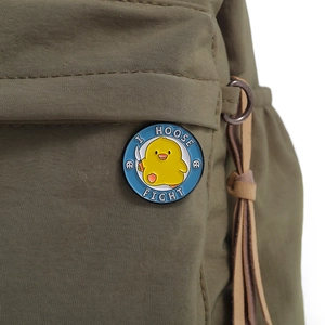 Detail of round enamel duck badge with 'I CHOOSE FIGHT' text pinned on a green bag