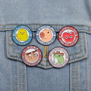 Set of five cartoon enamel pins with sloth and frog designs on a blue denim jacket pocket