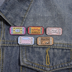 Set of five colorful enamel pins with movie ticket design pinned to a denim jacket pocket