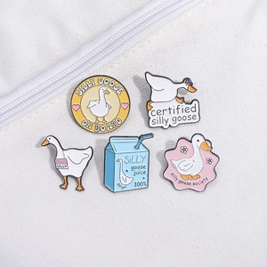 Five pieces of silly goose enamel pin set with milk box and floral designs on white fabric