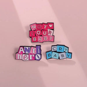 Set aus Emaille-Pins in Rosa und Blau mit den Texten NOT YOUR BABY, ANTI hero und CRY BABY