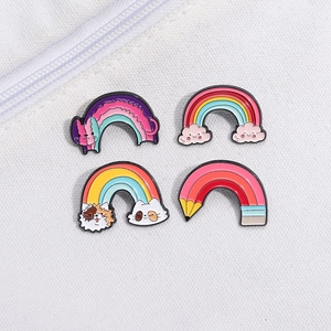 Set of four colorful rainbow cat enamel pins with cartoon clouds and pencils motifs