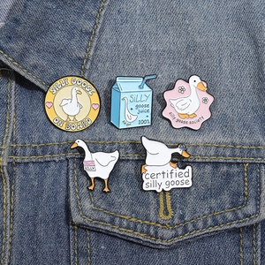 Set of five cute cartoon goose enamel pins and silly goose milk box badges on denim