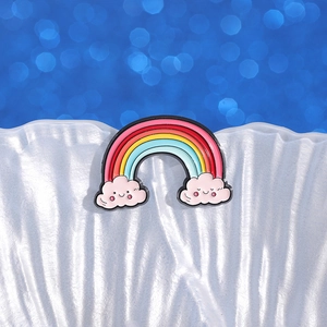 Cute enamel rainbow brooch with smiling pink clouds on a white shell display base