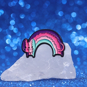 Cute enamel cat brooch with rainbow gradient colors on white stones and blue bokeh