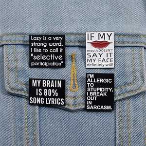 Détail de quatre épingles en émail rectangulaires avec citations sur tissu denim