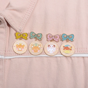 Detail von vier niedlichen Tier-Emaille-Pins mit bunten Schleifen auf rosa Denim