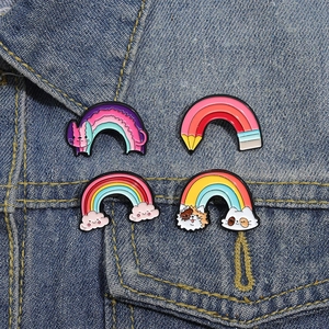 Set of four colorful rainbow cat enamel pins on blue denim jacket accessory