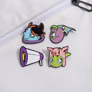 Detail of four creative enamel pins with cartoon monster designs on white canvas fabric