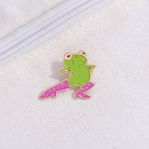 Macro d'un pin's grenouille en émail vert avec bottes roses pailletées sur toile