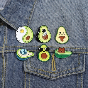 Set of six creative avocado enamel pins on denim jacket showing cute cartoon designs