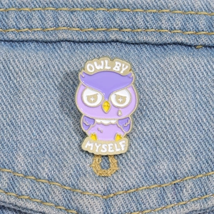 Detail of purple owl enamel pin with 'OWL BY MYSELF' text on blue denim fabric