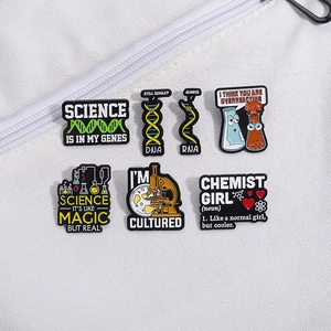 Set of 6 cartoon science enamel pins with DNA, microscope, and beaker on white fabric
