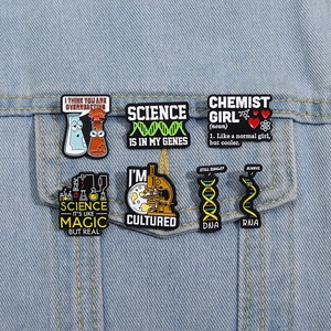 Creative science themed enamel pins set with DNA and chemistry designs on denim jacket