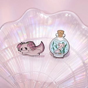 Cute pink axolotl and message bottle enamel pins set on decorative glass tray