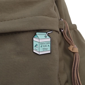 Close-up of a cute milk carton enamel pin on a green canvas bag with medical student tears