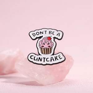 Spilla cupcake in smalto rosa con scritta Don't Be A Cuntcake su sfondo rosa soft