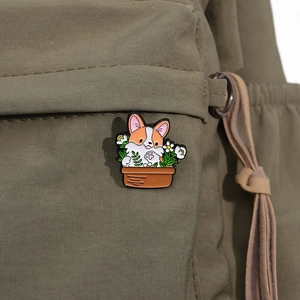 Broche en émail avec Corgi dans un pot de fleurs épinglée sur un sac en toile vert