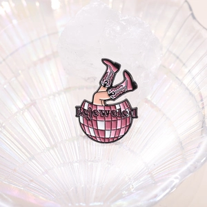 Détail de pin's émaillé avec boule disco rose, bottes de cowboy et texte Bejeweled
