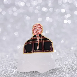 Broche en émail montrant une tresse et une chemise à carreaux sur fond flou bokeh