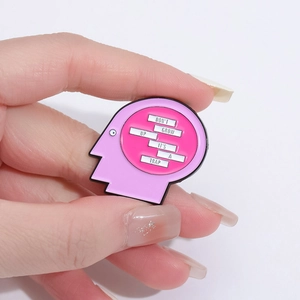 Pink and purple enamel brooch with Don't Grow Up It's a Trap slogan on white background