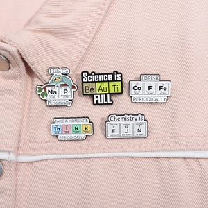 Set of 5 science enamel pins featuring chemical element symbols on a denim jacket