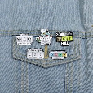 Five science-themed enamel pins spelling out words like COFFEE on a denim jacket pocket