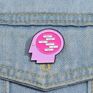 Close-up of pink face silhouette enamel pin on denim jacket with Don't Grow Up slogan