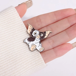 Cute cartoon enamel Gizmo animal pin displayed on white knitted sweater fabric