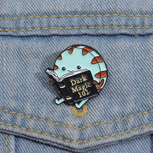 Detailed view of Peppermint Butler enamel pin holding a Dark Magic book on denim jacket