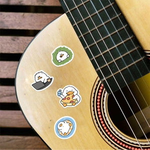 Detail shot of four cute cartoon duck stickers applied to a wooden guitar surface