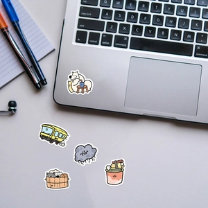 Close-up of five cute waterproof animal stickers on a white desk with a laptop