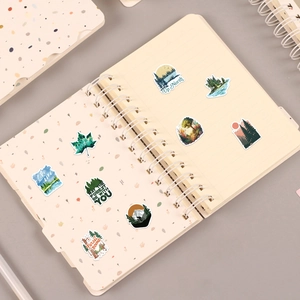Detail of waterproof green forest landscape stickers on a notebook featuring lake and mountain