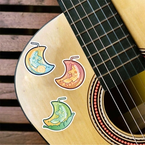 Crescent moon animal stickers with drink cups decorating a wooden acoustic guitar body