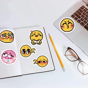 Detail von gelben Emoji-Graffiti-Aufklebern auf weißem Tisch mit Laptop und Brille