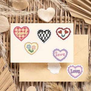 Close-up of heart-shaped doodle stickers with plaid and floral patterns on vintage envelopes