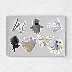 Detailed view of silver metallic skull stickers and butterfly accessories on grey board