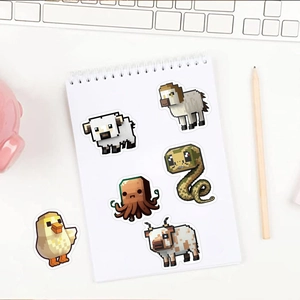 Macro shot of 6 pixel art animal stickers on a spiral notebook with a cozy desk setup