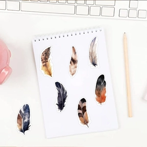 Close-up van aquarel veren stickers op een notitieboekje met een lichte bureau-achtergrond