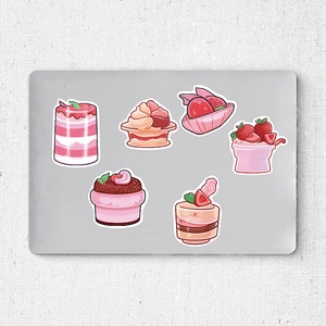 Dettaglio di adesivi rosa per dolci con bordi bianchi su un laptop metallico