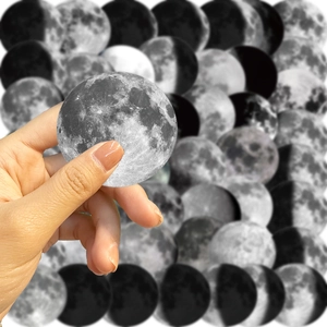 Close-up of hand holding a waterproof black and white moon phase graffiti sticker