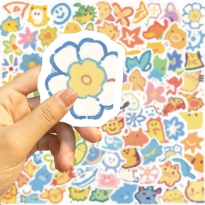 Close-up of a hand holding a blue flower sticker from a waterproof cartoon sticker set