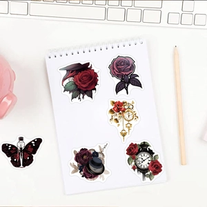 Close-up of gothic punk rose and clock stickers on a white notebook with creative desk decor
