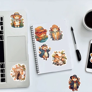 Cute cartoon orange cat stickers decorating a laptop and notebook on a white desk
