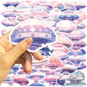 Close-up of pastel cartoon UFO sticker with white die-cut edge held in hand