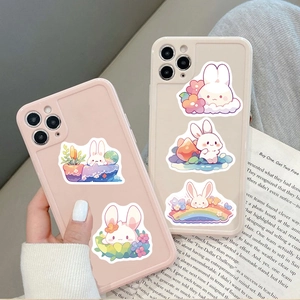 Dettagli di simpatici adesivi con coniglietti su cover per iPhone rosa e crema con luce soffusa