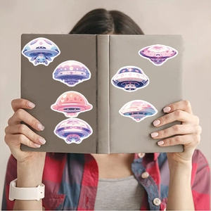 Detailed view of colorful cartoon UFO stickers applied to a grey notebook cover decoration